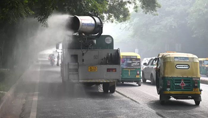 Commuters ride past an anti-smog gun spraying water to curb air pollution amid heavy smog conditions in New Delhi on November 4, 2022 || AFP Photo: Collected  