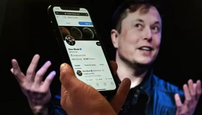In this file photo illustration taken on April 14, 2022 a phone screen displays the Twitter account of Elon Musk with a photo of him shown in the background, in Washington, DC || AFP Photo: Collected