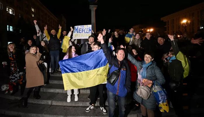 People hold a Ukranian flag and a slogan which reads as "11/11/2022 - Kherson - Ukraine" as they gather in Maidan Square to celebrate the liberation of Kherson, in Kyiv on November 11, 2022 || AFP Photo