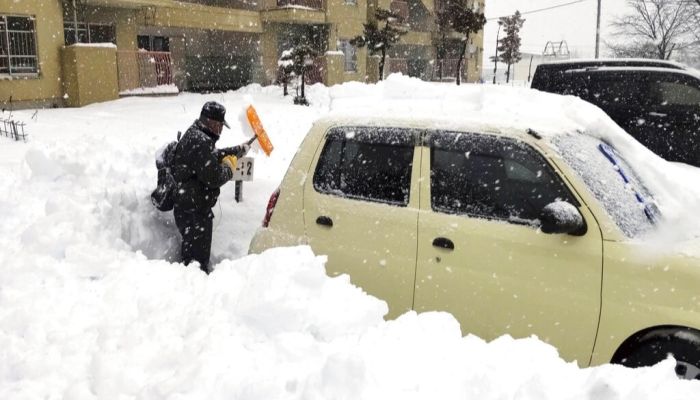 A resident shovels snow off around a car at a parking lot in Kitami city Hokkaido prefecture, northern Japan, on Dec. 24 2022 || Photo: AP