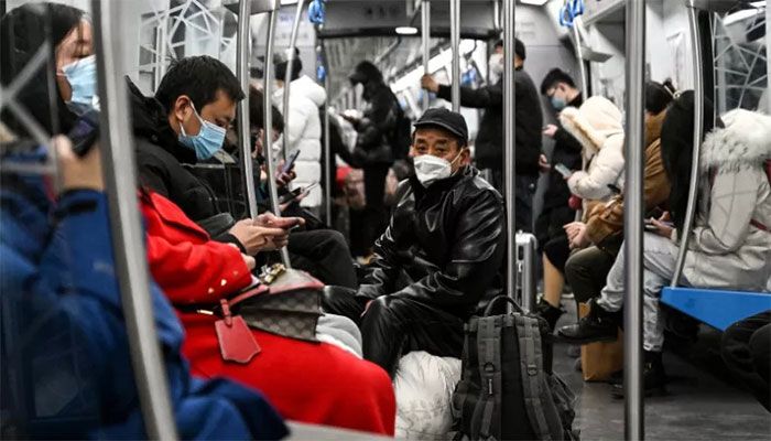 People wear face masks on a train amid the Covid-19 pandemic in Beijing on December 19, 2022 || AFP Photo