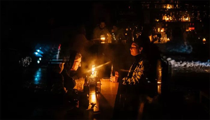 People sit at a candlelit table in a bar in the centre of Kyiv, during a blackout, after Russian strikes targeted the power infrastructure on December 16, 2022 || AFP Photo