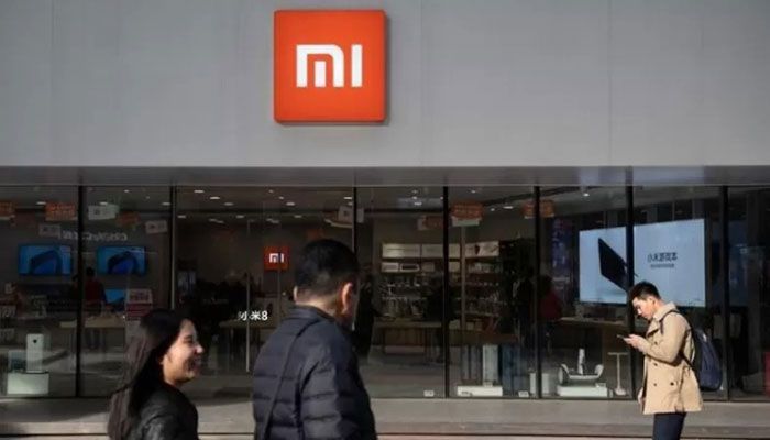 People walk past a Xiaomi shop in Beijing || AFP Photo