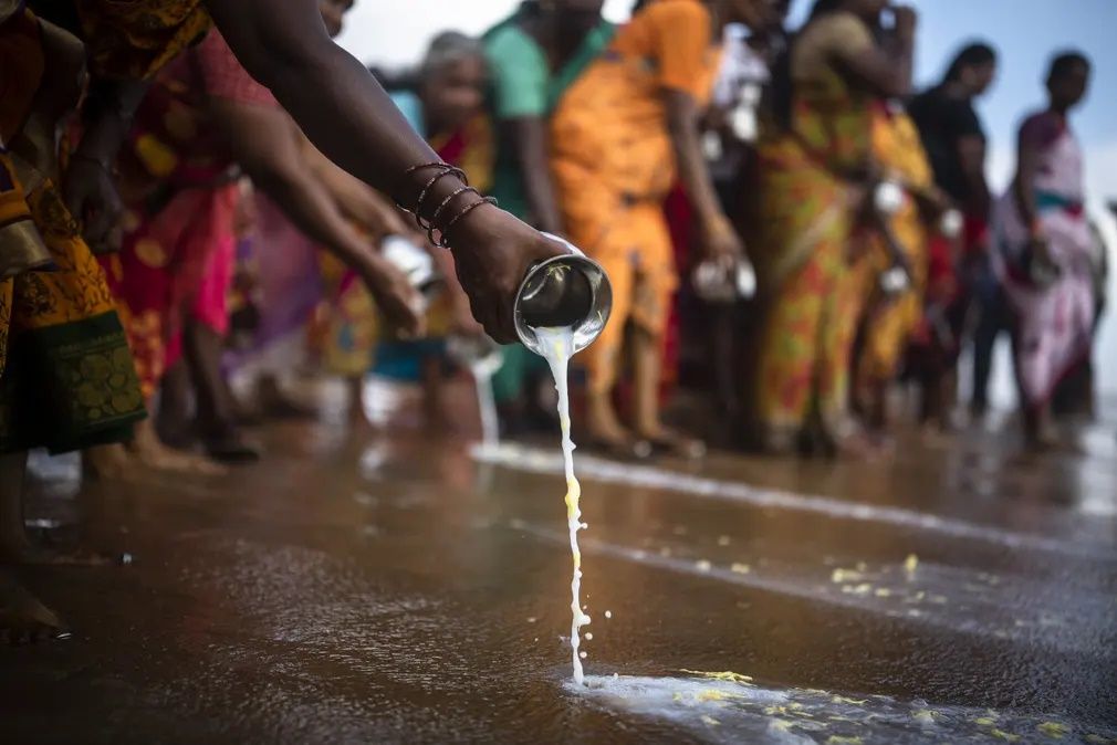 People pour milk in the waters of the Bay of Bengal as they pay homage to the victims of the 2004 Indian Ocean tsunami, during a prayer ceremony at Nochikuppam beach in Chennai to mark the 18th anniversary of the tragedy || Photo: EPA