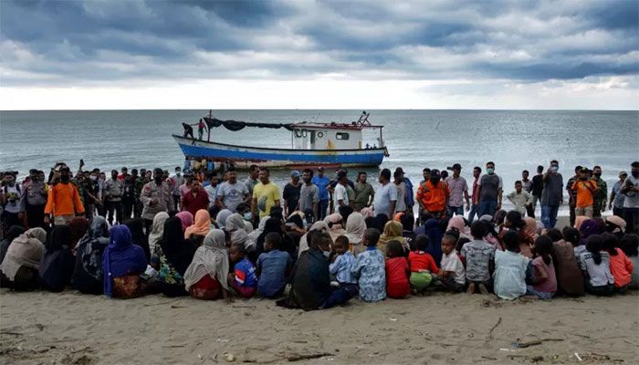 Rohingya from Myanmar sit on the shorelines of Lancok village, in Indonesia's North Aceh Regency, after some 100 including 30 children were rescued from a wooden boat off the coast of Indonesian island of Sumatra. || AFP Photo 