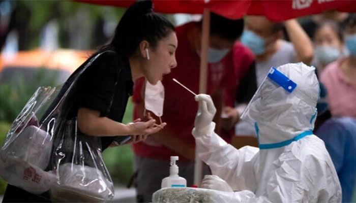 A worker wearing a protective suit swabs a woman's throat for a COVID-19 test at a coronavirus testing site in Beijing, Friday, August 26, 2022. || AP File Photo