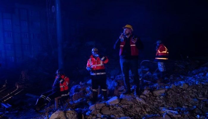Rescue workers take rest as others search for victims at a collapsed building after a 6,4-magnitude second earthquake hit the Hatay province in southern Turkey, in Antakya, on February 20, 2023, two weeks after a 7,8-magnitude one hit the first time the same region. || AFP photo.