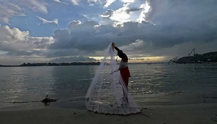 A fisherman arranges his fishing net at a beach against the backdrop of pre-monsoon clouds in the southern Indian city of Kochi, Jun 5, 2014 || Photo: REUTERS