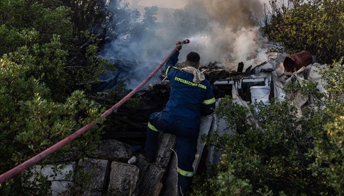 A firefighter battles a wildfire in Agia Sotira, a western suburb of Athens, Greece.