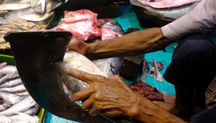 The seller is cutting the fish into pieces.