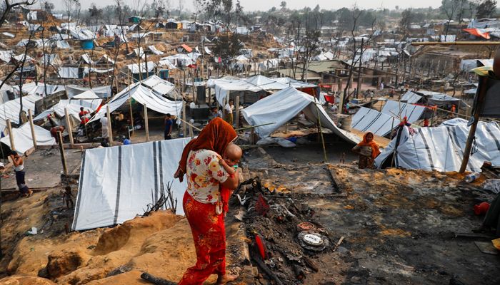 Rohingya refugee camp following massive fire in Cox's Bazar
A Rohingya refugee woman carries her child after a massive fire broke out  || Photo: Reuters