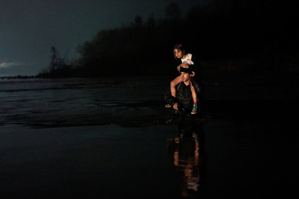 (Eagle Pass, Texas, US) A man carries a young girl on his shoulders as he and a group of several hundred people wade across the Rio Grande into Eagle Pass from Piedras Negras in Mexico || Photograph: Cheney Orr/Reuters