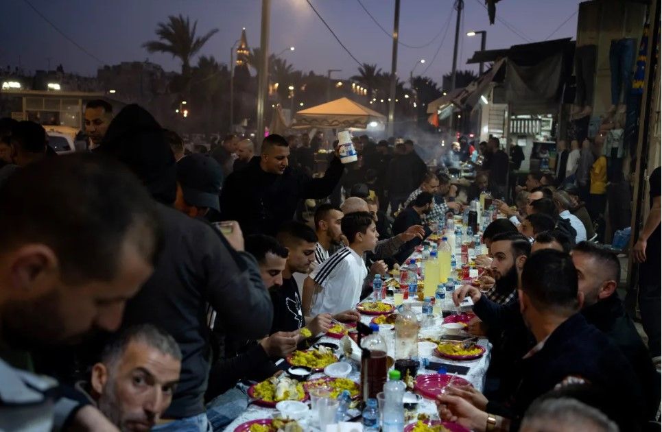 Muslims break their fast with the iftar meal after the last Friday prayers of the fasting month of Ramadan, outside the Old City of Jerusalem