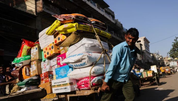 A Labourer Reacts As He Transports A Cart Full Of Sacks At A Wholesale Market In The Old Quarters Of Delhi, India. File Photo 